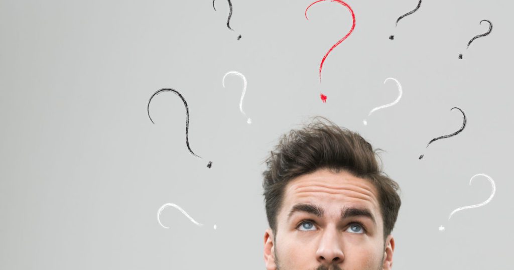 thinking man with many question marks above his head, against grey background