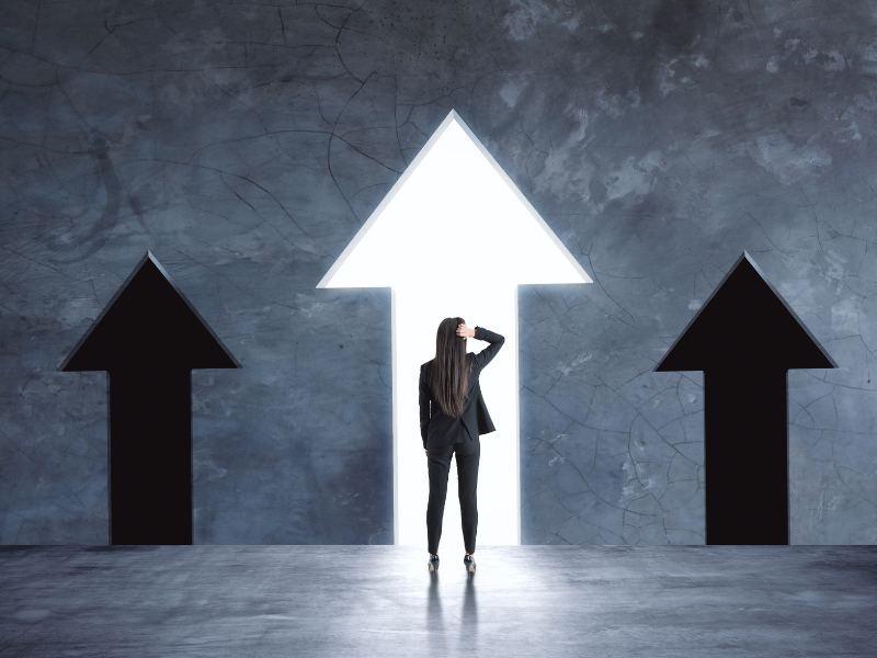 Woman standing in front of arrows pointing straight ahead