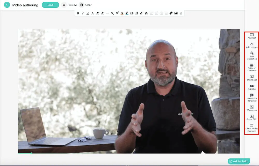 Man sitting next to laptop talking with his hands wearing a LearnWorlds black polo