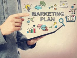 Marketing your online course - photo of hands holding table with text "Marketing Plan"