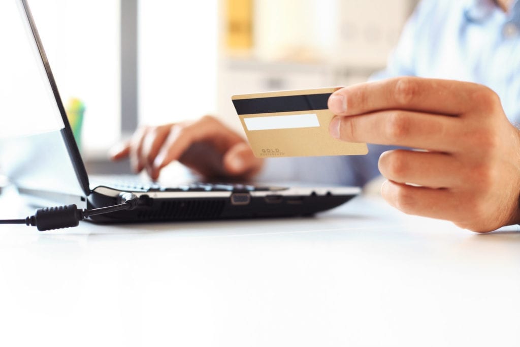 Close up of a man shopping online using laptop with credit card