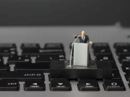 Toy man at podium on laptop