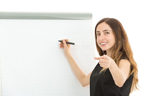 Woman at flip chart pointing at viewer - marketing teaching similarities
