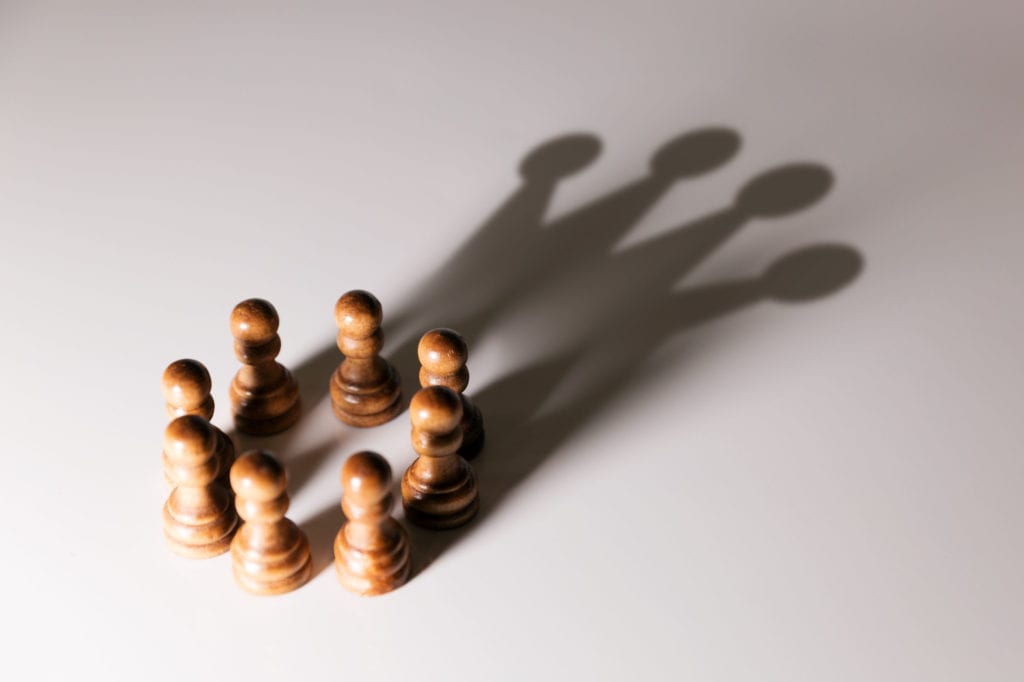 Photo of six chess pieces casting crown shadow for leading learning concept