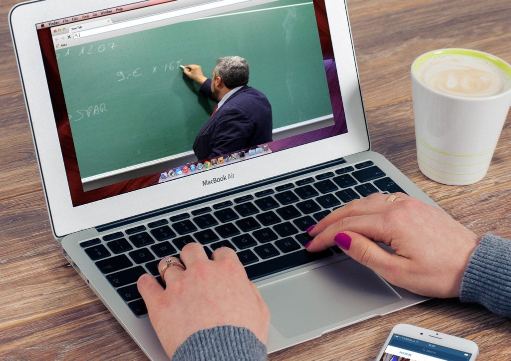 Hands on laptop with online masterclass on screen
