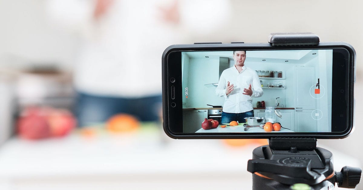Man on the kitchen filming video. Video content marketing concept.