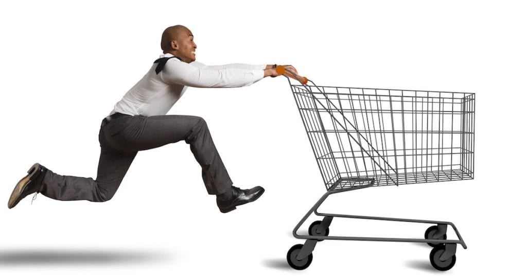 Man in suit pants, tie running with shopping cart - Black Friday concept