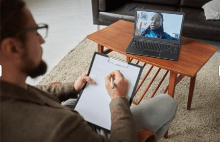 man follows an online coaching session on his laptop