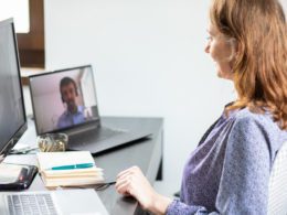 Woman at desk talking to man on laptop for online coaching business concept