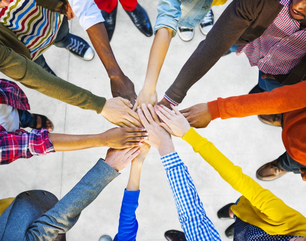 Diverse, mutli-ethnic hands reaching into circle for learning community concept
