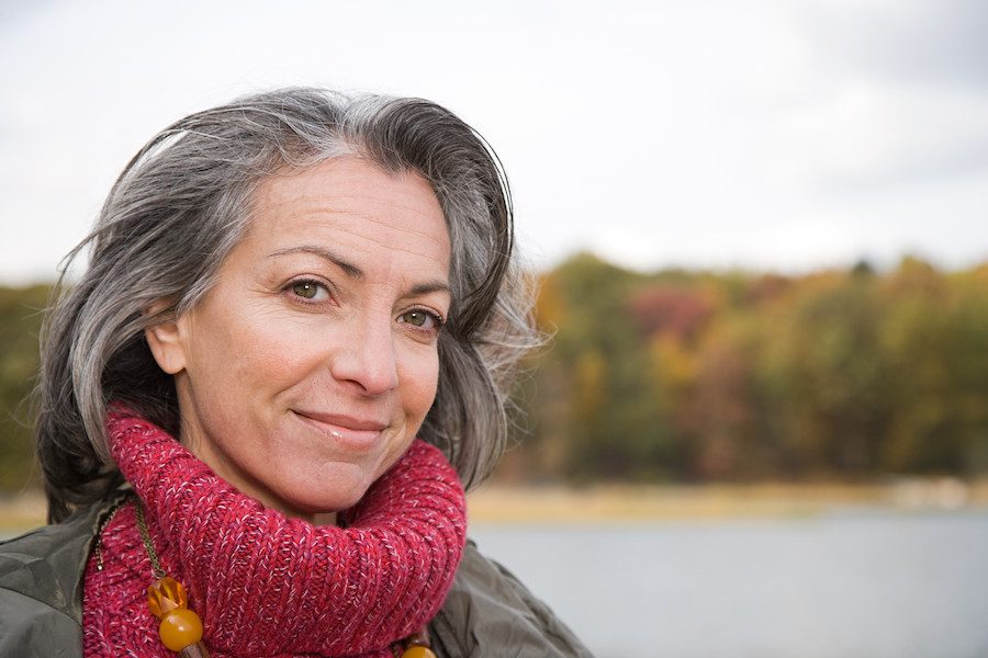Middle aged Caucasian woman with graying longish hair and red turtleneck sweater looking at the camera
